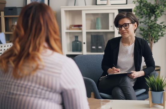 duas mulheres adultas sentadas uma de frente para outra
